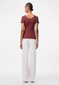 Burgundia soonikuga lühikeste varrukatega pluus, millel on avatud kaelus, koos valgete laia säärega teksadega. Sile tekstuur, kujundatud sobivaks väljanägemiseks.