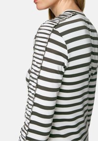 Gestreiftes Langarmoberteil in Weiß und Olivgrün, mit einem strukturierten Rüschendetail entlang der Schulternaht, aus einem weichen Baumwoll-Mix.