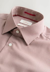 Collet et partie avant supérieure d'une chemise habillée en coton à micro-carreaux rouges et blancs avec des boutons blancs et des étiquettes de marque à l'intérieur du col.