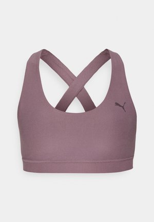 Αθλητικό σουτιέν από μαλακό, ελαστικό ύφασμα. Το χρώμα είναι ανθεκτικό μοβ, με σχέδιο racerback και σταυρωτούς ιμάντες, και ένα μικρό μαύρο λογότυπο.