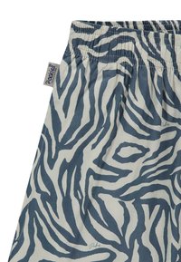 Țesătură din bumbac cu un model de dungi zebra alb și albastru. Talie elastică cu etichetă de marcă pe lateral. Textură netedă.