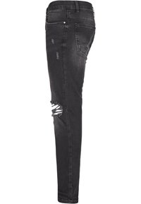 Crni traper skinny traperice s izlizanim detaljima na koljenu, dizajn s pet džepova i metalni gumb za zatvaranje. Jasno šivenje i mekana tekstura.