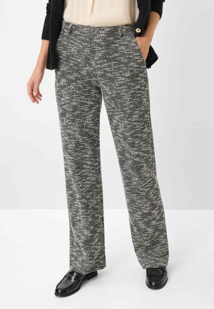 Pantalons en tissu tissé texturé noir et blanc, présentant un design à jambe droite et des poches latérales, associés à des chaussures noires.