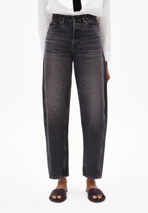 Vervaagde zwarte high-waisted jeans met rechte pijpen, gedragen met zwarte open-toe slides en een wit overhemd.