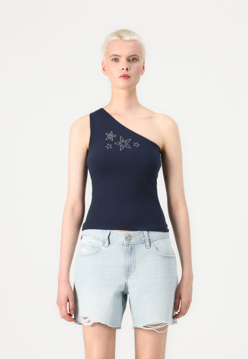 Mørkeblå, enkel- skulder topp med stjerneformede rhinestone-dekorasjoner; kombinert med lyseblå, slitte denimshorts.