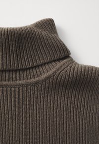 Rebrasta turtleneck vunena majica u tamnosmeđoj boji. Ima visoki ovratnik i teksturirani uzorak, sa mekanim, pletenim završetkom.