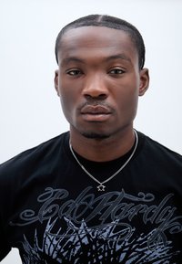 Tricou negru cu un design grafic albastru deschis, prezentând un colier cu o_CHAINĂ_ de argint și un pandantiv circular. Prim-plan al părții superioare a corpului.