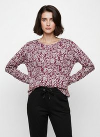 Maglietta a maniche lunghe color marsala con motivo floreale bianco, scollatura rotonda, vestibilità rilassata, abbinata a pantaloni neri con coulisse.