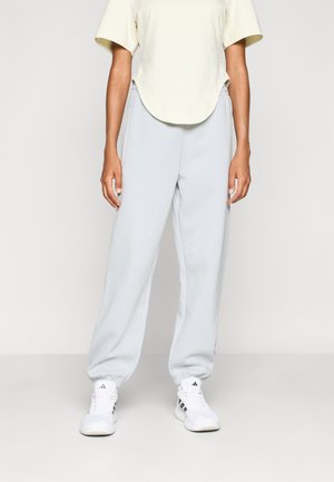Light gray sweatpants with an elastic waistband and cuffs, paired with a pale yellow t-shirt. White athletic shoes complete the outfit.