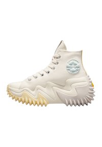 Höga sneakers i vit kanvas, med en taggig gummisula i kräm och gult, en blå stjärnlogotyp på sidan och silverfärgade öglor.