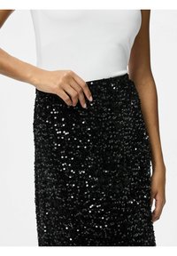 Sorte paljetteret nederdel med et tætsiddende design. Skinnende, runde paljetter dækker stoffet og reflekterer lys. Elastisk talje.