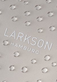 Tessuto beige chiaro con texture a punti in rilievo, caratterizzato dal testo in rilievo "LARKSON HAMBURG" in bianco. Superficie liscia, motivo sottile.