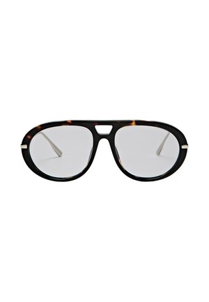 Lunettes d’aviateur surdimensionnées avec verres transparents et monture en écaille foncée, avec une petite découpe triangulaire sur le pont.
