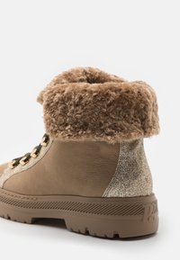 Brune læderankelstøvle med en faux fur-krave, glitrende detaljer, snørebånd foran, guldfarvet hardware og en struktureret gummisål.