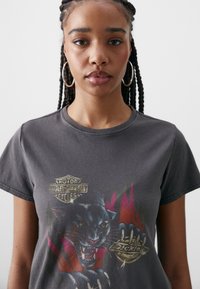 Grå grafisk t-shirt med en design av en svart panter och logotyper för Harley-Davidson och Dickies. Tillverkad av bomull med en klassisk rund halsringning.