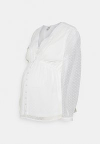 Blusa da maternità bianca con pois testurizzati, chiusura a bottoni, scollatura a V e vita arricciata. Presenta maniche lunghe e trasparenti e un tessuto morbido.