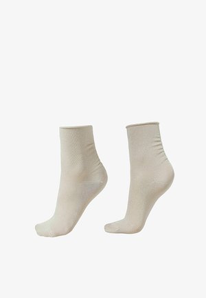 Chaussettes beiges montantes avec une texture lisse et brillante. Pointe arrondie et bord élastique pour un ajustement parfait. Pas de motifs ou d'accessoires visibles.