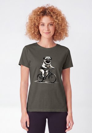 Vrouw met krullend haar die een donker T-shirt draagt met een tekening van een mopshond die op een fiets rijdt.