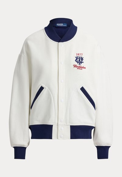 White varsity jacket with navy collar, cuffs, and waist, featuring "1877 Wimbledon Polo" embroidery and diagonal navy-trimmed front pockets.