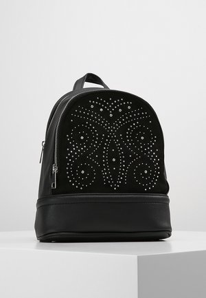 Schwarzer Leder-Rucksack mit silbernem Nieten-Schwirlmuster auf der Vordertasche und Reißverschluss, präsentiert auf einem weißen Podest.