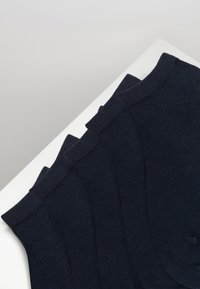Marineblå sokker, ribbet tekstur, flat strikkedesign, med forsterkede mansjetter på toppen. Arrangementet viser fem par stablet.