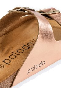 Rosa guld, metallisk lädersandal med två remmar och en spänne. Har en mjuk, brun innerfoder och en vit, texturerad sula.