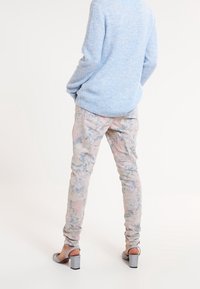 Ljusblått stickat tröja i kombination med pastellfärgade blommönstrade skinny-byxor. Chunky grå klacksandaler fulländar outfiten.