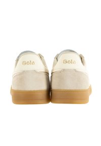 Ett par beige sneakers med mockatextur, gummisula och silverdetaljer samt "Gola"-logotyp på baksidan.