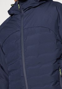 Marinblå isolerad jacka med slät yta, utrustad med full dragkedja, huva och en kontrasterande ljusgrön dragkedjeöppnare.