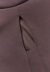 Mauve látka s hladkým povrchem má výřez, který odhaluje světlejší vnitřní vrstvu. Přesný střih a precizní šití.