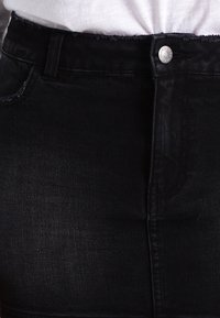 Czarne dżinsy z wysokim stanem, z metalowym zapięciem, przeszyciami i lekko postrzępionym dołem.