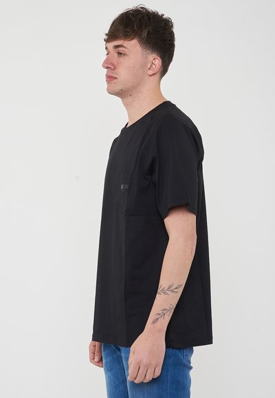 T-shirt nero a maniche corte con scollatura rotonda, tasca sul petto e vestibilità rilassata. Realizzato in tessuto di cotone, dalla consistenza morbida.