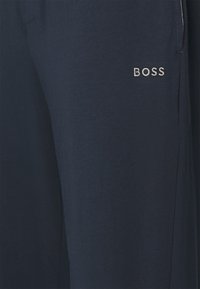 Marinblå joggingbyxor i mjukt bomullsmaterial, med en diskret "BOSS"-logotyp i vit brodyr på vänster lår.