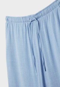 Pantalon bleu clair à coupe décontractée, fabriqué en tissu texturé. Doté d'une taille élastique avec un cordon de serrage pour un ajustement personnalisable.