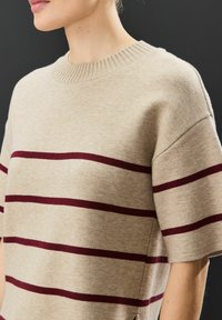 Beige strikket sweater med kortærmer, prydet med vinrøde vandrette striber, ribbet halsudskæring og sideslids for ekstra detaljer.
