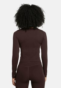 Long-sleeve, fitted top in dark brown fabric, featuring a smooth texture and a cropped design. Includes seam detailing along the back.