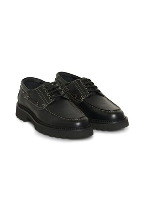 Paar schwarze Leder-Schnürbootschuhe mit dicken Sohlen und weißen Nähten, nebeneinander auf weißem Hintergrund positioniert.