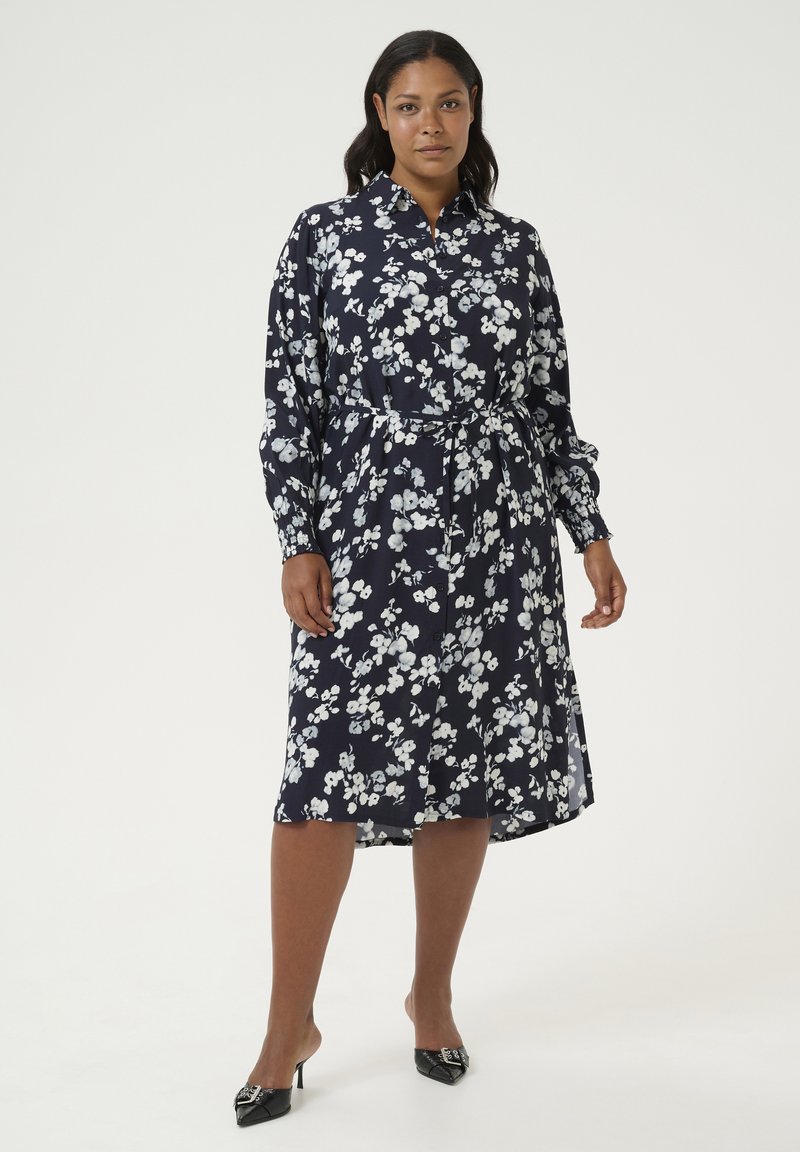 Marineblauwe bloemen midi-jurk met lange mouwen, een riem in de taille en knoopsluiting. Kenmerkt zich door witte bloemmotieven en een gladde stoftextuur.
