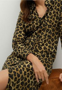 Pitkähihaisessa leopardikuosisessa mekossa on ruskeita ja mustia pilkkuja vaaleanruskealla taustalla. Pehmeä kangas, napitettava etuosa ja kaulus.