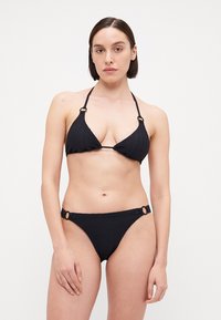 Svart bikini med en teksturert trekantet topp og lavt utskårede bukser med sirkulære detaljer på sidene.