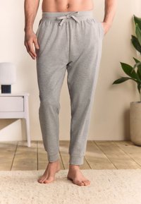 Pantaloni jogger in cotone grigio con vita elasticizzata e coulisse. Dotati di tasche laterali e polsini a coste alle caviglie, vestibilità casual.