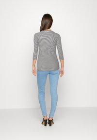 Grå och vit randig långärmad topp med trekvartslånga ärmar, kombinerad med ljusblå skinny jeans och svarta klacksandaler.