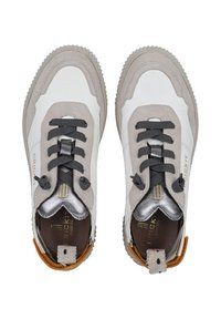 Sneaker grigio e bianco con tomaia in pelle strutturata e rete, dotata di lacci grigi, un accento metallico e un tassello sul tallone marrone.