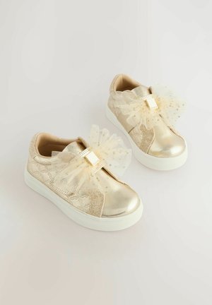 Le sneakers metallizzati oropresentano un design tessurizzato, una morbida fodera beige e un fiocco decorativo in tulle con pois dorati sul cinturino in velcro.
