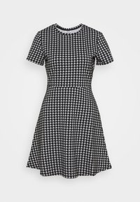 Kortärmad svartvit klänning med ett hundtandsmönster, åtsittande midja och utsvängd kjol. Rund halsringning och mjuk textur.