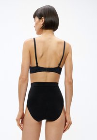 Sutien negru cu bretele reglabile și închidere cu cârlig, asortat cu chiloți negri cu talie înaltă. Material neted și elastic, cu cusături minimale.