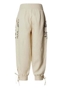 Pantalon ample beige avec poignets élastiques et détails de liens aux chevilles, présentant une broderie florale noire le long des côtés extérieurs.