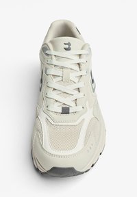 Svetlohnedá športová obuv so sieťovanou a syntetickou vrchnou časťou, vystlaným jazykom, plochými bielymi šnúrkami a čiernym logom. Gumová podošva s textúrovaným gripom.