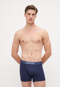 Marinblå bomullsboxershorts med en kontrasterande mörkblå elastisk midja som har Levi's-logotypen i ljusgrå.