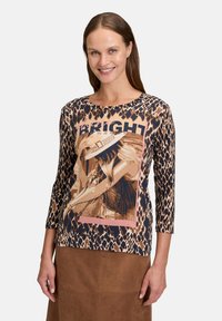 Długirękawowa bluzka w brązowo-beżowy wzór w panterk�ę z graficznym napisem "BRIGHT" w różowym kolorze, z okrągłym dekoltem i dopasowanym krojem.